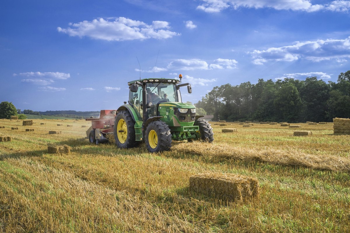 Traktor mit Anbaugerät bei der Arbeit auf einem abgeernteten Feld